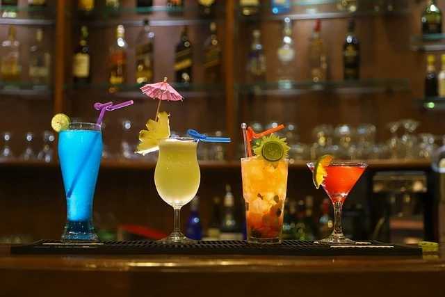 Un groupe de boissons colorées sont alignés sur un bar.