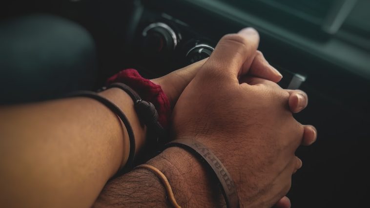 Un homme et une femme se tenant la main dans une voiture.