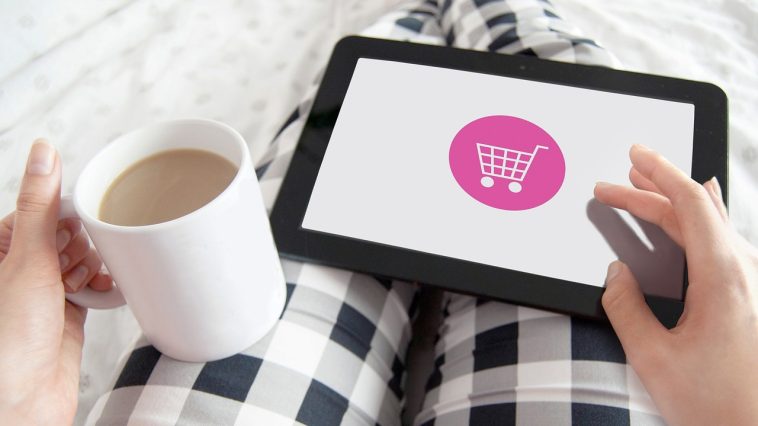 Une femme tenant une tablette avec une icône de panier dessus.