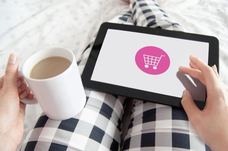 Une femme tenant une tablette avec une icône de panier dessus.