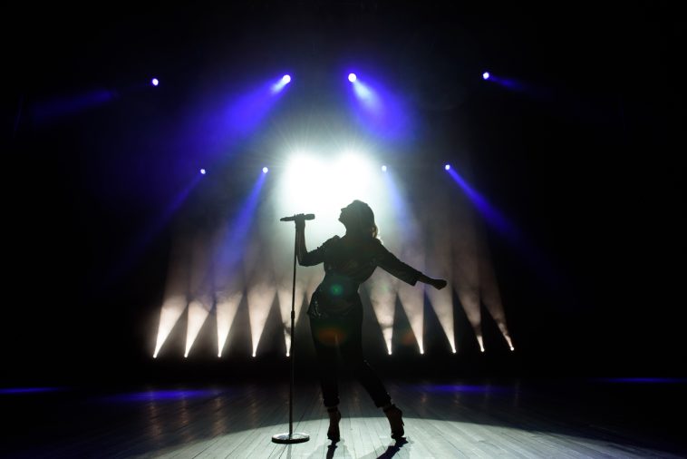 Une silhouette de femme chantant sur scène.