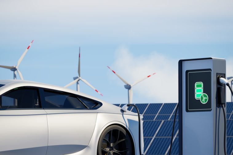 Une voiture blanche est garée devant des éoliennes.