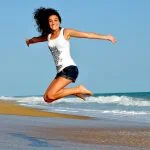 Une femme sautant en l’air sur une plage.