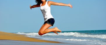 Une femme sautant en l’air sur une plage.