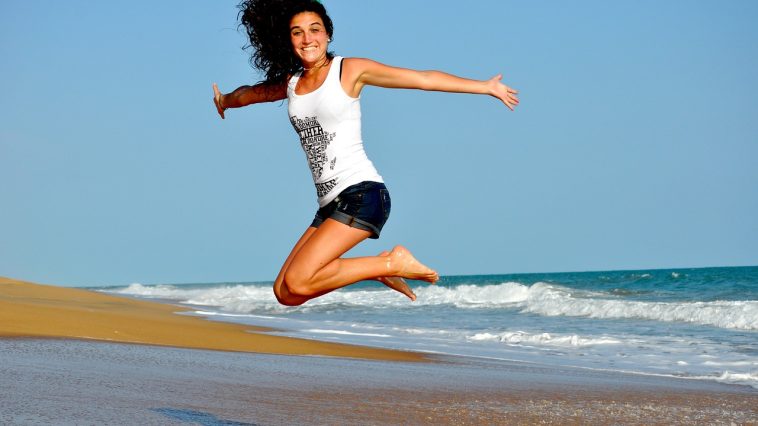 Une femme sautant en l’air sur une plage.