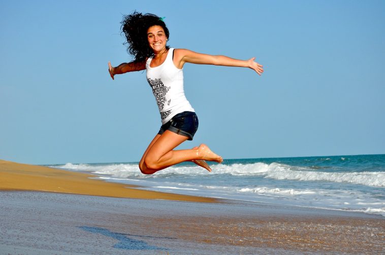 Une femme sautant en l’air sur une plage.