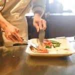 Un chef coupant un morceau de viande dans une assiette.