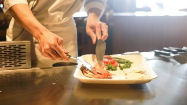 Un chef coupant un morceau de viande dans une assiette.