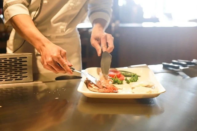 Un chef coupant un morceau de viande dans une assiette.