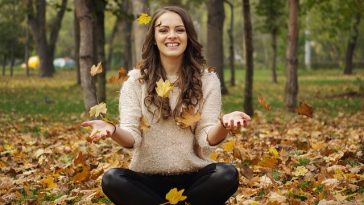 Une jeune femme assise par terre, les mains tendues, découvrant des techniques pour renforcer sa confiance en elle pour un quotidien plus heureux.