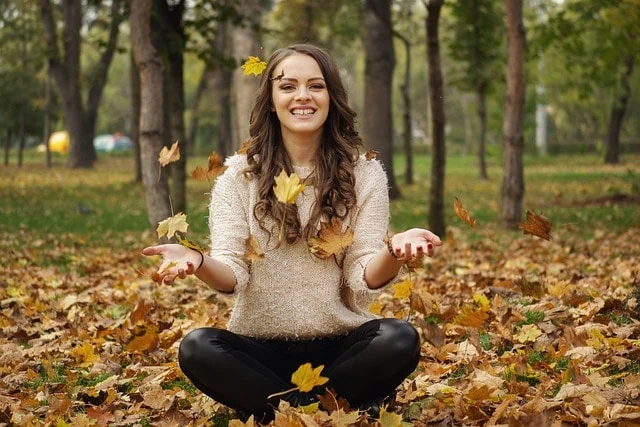 Une jeune femme assise par terre, les mains tendues, découvrant des techniques pour renforcer sa confiance en elle pour un quotidien plus heureux.