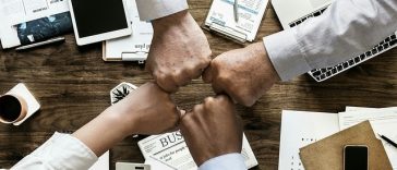 Un groupe d’hommes d’affaires formant un poing autour d’un bureau.