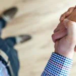 Un homme et une femme se tenant la main sur un plancher en bois.