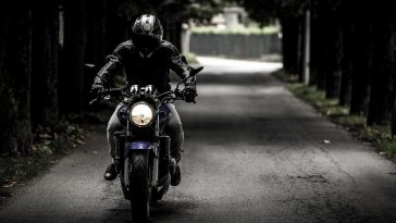 Une personne conduisant une moto sur une route sombre équipée d'accessoires.