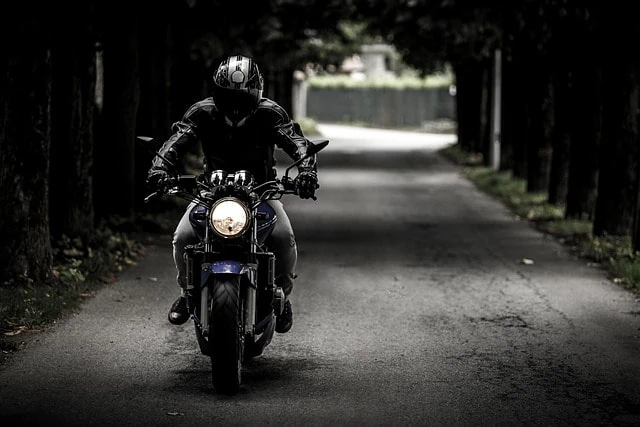 Une personne conduisant une moto sur une route sombre équipée d'accessoires.