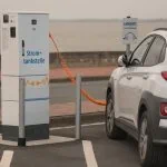 Une voiture électrique blanche est branchée sur une borne de recharge.