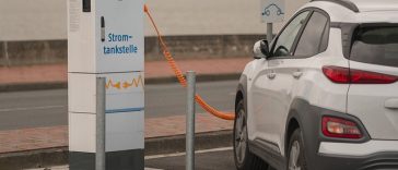 Une voiture électrique blanche est branchée sur une borne de recharge.