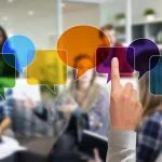 Une personne montrant des bulles colorées recouvrant un groupe diversifié de collègues de travail dans une salle de réunion.
