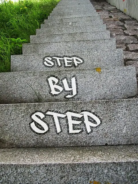 Escalier en béton avec "étapes clés" peintes sur les marches, entouré de verdure.