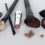 Produits de maquillage assortis et pinceaux sur une surface blanche pour sublimer la peau mature.