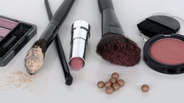 Produits de maquillage assortis et pinceaux sur une surface blanche pour sublimer la peau mature.