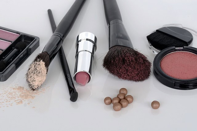 Produits de maquillage assortis et pinceaux sur une surface blanche pour sublimer la peau mature.