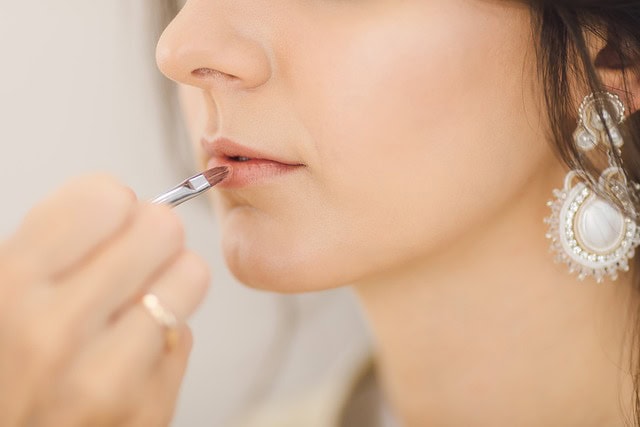 Application du rouge à lèvres : une vue rapprochée des lèvres d'une femme en guise de maquillage lumineux est soigneusement appliquée.