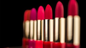 Une gamme de différentes nuances de rouge à lèvres et de rouges à lèvres sur fond sombre.