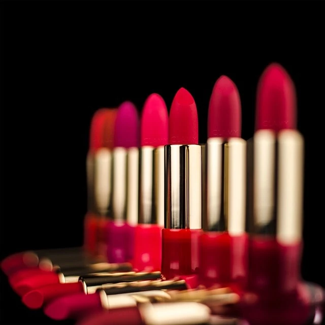 Une gamme de différentes nuances de rouge à lèvres et de rouges à lèvres sur fond sombre.