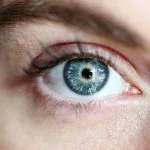Gros plan d'un œil humain montrant un iris et des cils bleus détaillés, se concentrant intensément, rehaussés par un maquillage subtil.