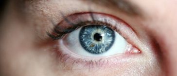 Gros plan d'un œil humain montrant un iris et des cils bleus détaillés, se concentrant intensément, rehaussés par un maquillage subtil.