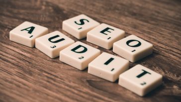 Les tuiles de Scrabble portant l'inscription « AUDIT SEO » sont soigneusement disposées sur une surface en bois, soulignant l'importance de réaliser un audit SEO efficace pour des performances Internet optimales du site.